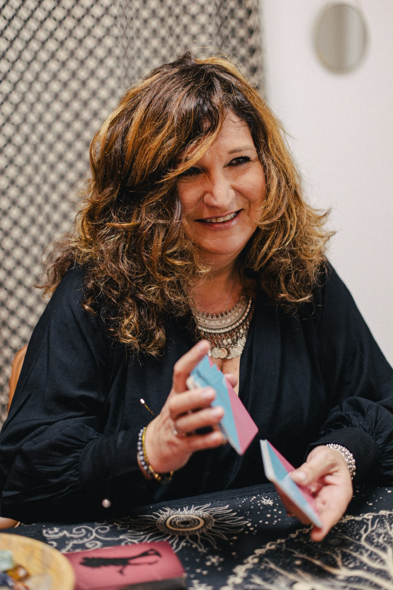 Portrait de Sylvie souriante, les cartes en main dans son cabinet
